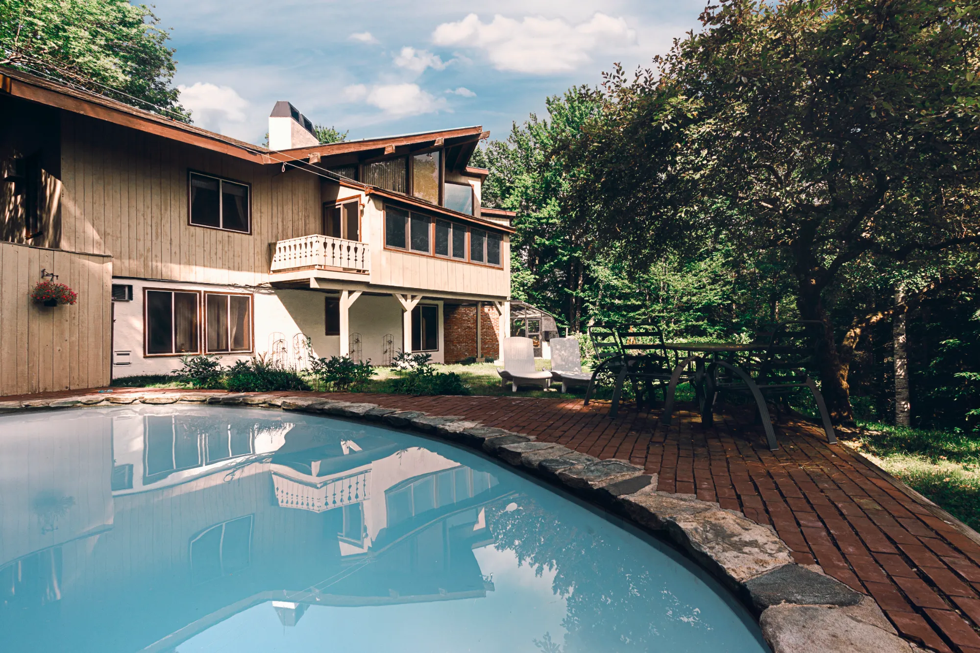 Paradise Vermont — secluded chalet with heated outdoor pool, brick patio, and surrounding woods near Stratton Mountain